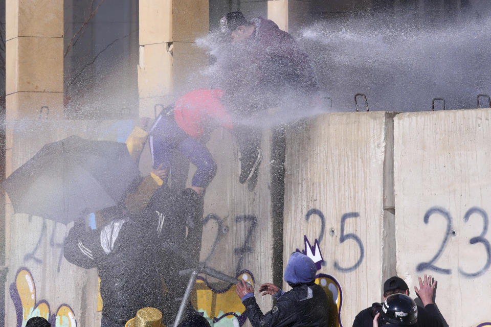 Riot police spray anti-government protesters with water cannons during a protest against a parliament session preparing a vote of confidence for the new government in downtown Beirut, Lebanon, Tuesday, Feb. 11, 2020. (AP Photo/Bilal Hussein)