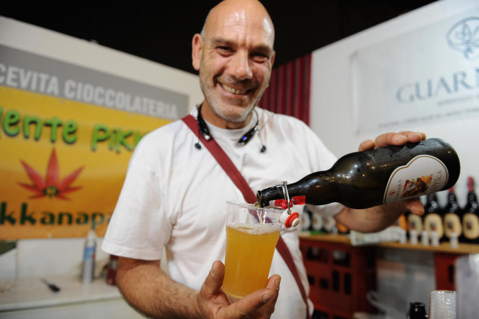 A smiling man pours a beer made with hemp into a glass