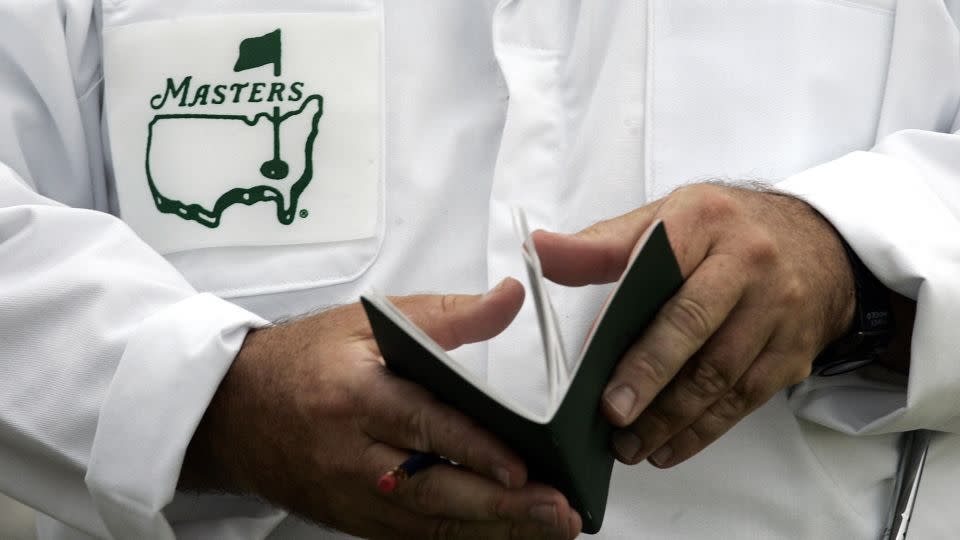 A caddie looks over his yardage book before the start of the first practice ahead of the 2006 Masters. - Timothy A. Clary/AFP/Getty Images