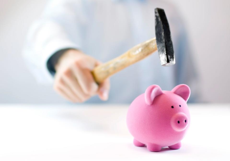 Pink piggy bank and hand with hammer