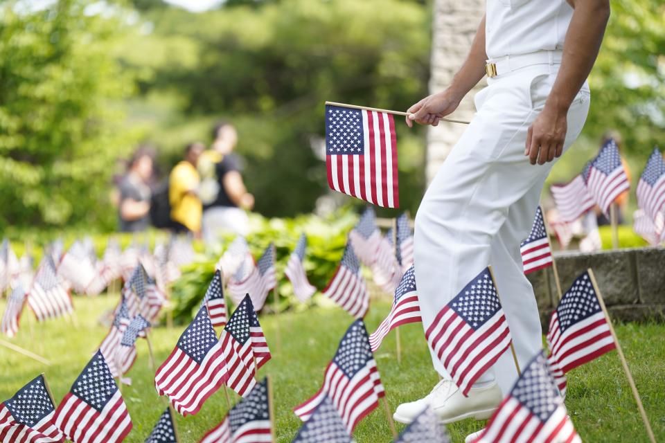 A U.S. Navy officer places an American flag in the lawn of Cliffside Park High School with student volunteers to honor those who died in combat ahead of Memorial Day on Monday, May 22, 2023.