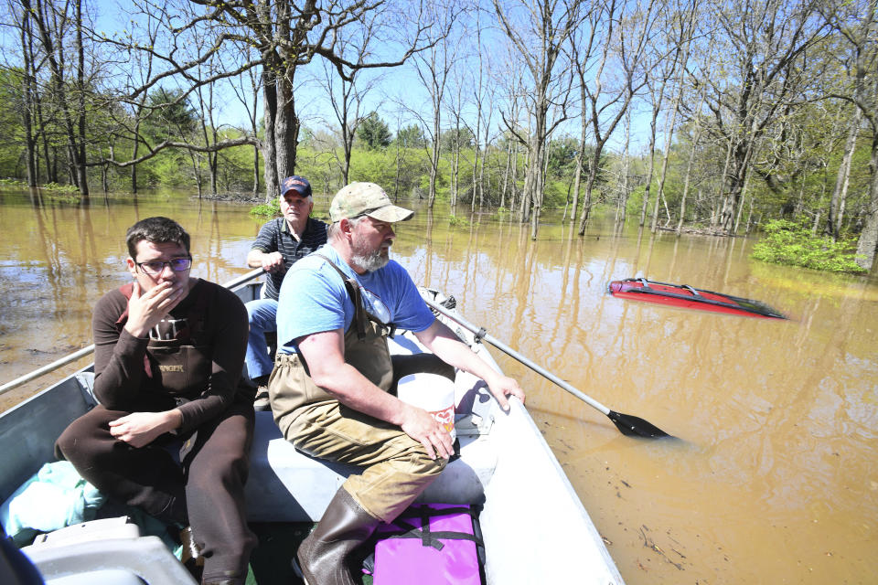 Don Thomas rows Nick Maki , left, and son Jason Thomas past Jason's red 2001 Jeep Grand Cherokee, barely visible above the flooding, after picking up Jason's two family cats from his flooded home in Midland. Jason Thomas said, "We walked out last night, me, my wife and three kids. Other than the pictures put up high or upstairs, everything else is gone." Breached dams further up the Tittabawassee River flooded downtown Midland, Mich. on Wednesday May 20, 2020. (Daniel Mears/ The Detroit News via AP)