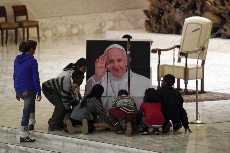 Children, assisted by volunteers of Santa Marta institute, compose a puzzle depicting Pope Francis before an audience in Paul VI hall at the Vatican December 14, 2013. REUTERS/Giampiero Sposito (VATICAN - Tags: RELIGION SOCIETY)