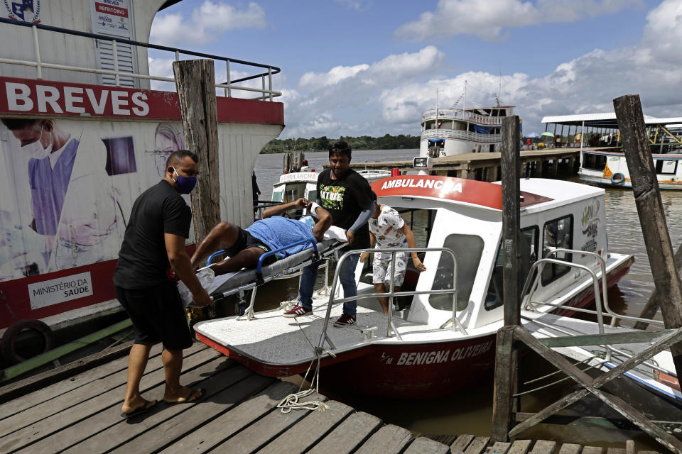 Health workers move a patient that is believed to be suffering from COVID-19 off a speed boat ambulance that provides medical care for riverside communities on the Amazon river, in the port city of Breves, located on the island of Marajo, Para state, on the mouth of the Amazon river, Brazil, Thursday, Dec. 3, 2020. Brazil is expecting a second wave of COVID-19 cases nationwide, with the state of Para reporting high numbers of people infected and more than 63 thousand dead from the disease so far. (AP Photo/Eraldo Peres)