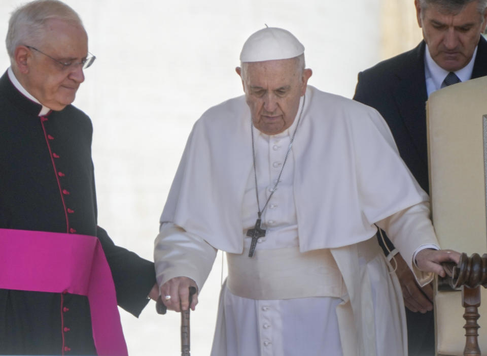 FILE - Pope Francis is helped by his aide Monsignor Leonardo Sapienza, left, as he walks with a cane to his weekly general audience in St. Peter's Square at The Vatican, on June 1, 2022. Pope Francis has revealed in an interview published Sunday Dec. 18, 2022 that shortly after being elected pontiff in 2013 he wrote a resignation letter in case medical problems impede him from carrying out duties. (AP Photo/Gregorio Borgia, File)