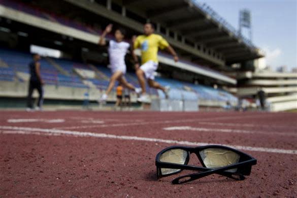 A pair of sunglasses, covered with tape, is seen on the track as its owner, a blind runner (back) from the Venezuelan Paralympics team, trains with a guide in Caracas April 17, 2012.