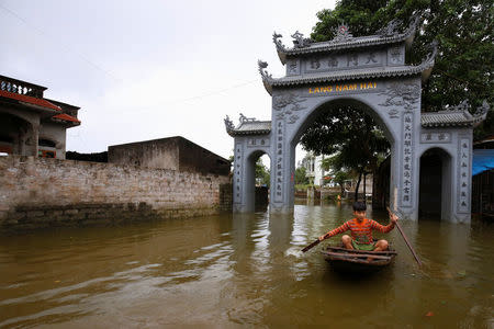 A boy paddles a boat past a flooded village's gate after a heavy rain caused by a tropical depression in Hanoi, Vietnam October 16, 2017. REUTERS/Kham