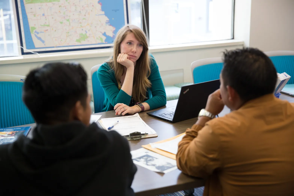 Lauren Koehler, the executive director of SFUSD’s Enrollment Center, listens as a man explains in Spanish that he’d like to enroll a 17-year-old in school despite not being listed on the adolescent’s birth certificate or any other record. The student arrived in the United States as an unaccompanied minor just days before the start of the 2023-24 school year. (Sonya Abrams/The Hechinger Report)