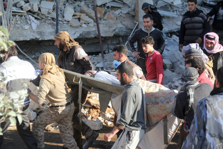 People carry a stretcher amid the debris after a hospital was hit by air strikes near Maaret al-Numan, in Syria's northern province of Idlib, on February 15, 2016