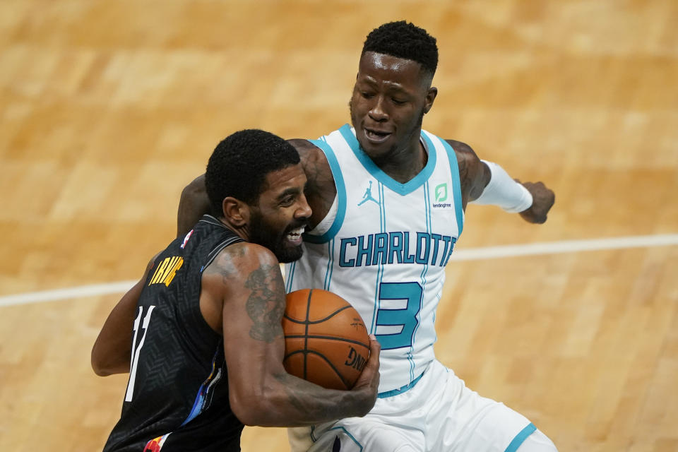 Brooklyn Nets guard Kyrie Irving drives around Charlotte Hornets guard Terry Rozier (3) during the first half of an NBA basketball game in Charlotte, N.C., Sunday, Dec. 27, 2020. (AP Photo/Chris Carlson)