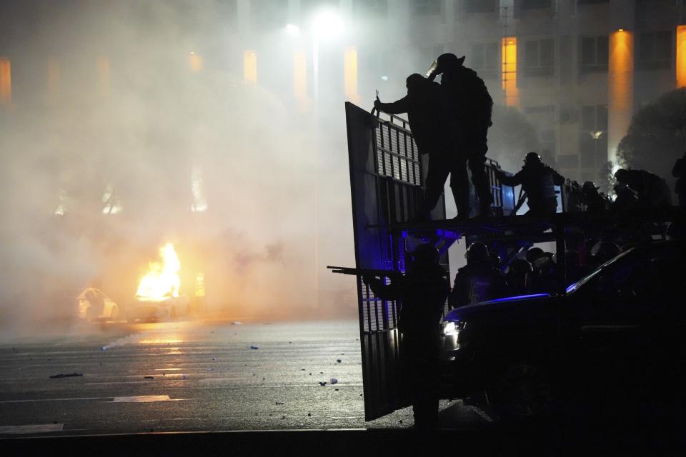 FILE - A police car on fire as riot police prepare to stop protesters in the center of Almaty, Kazakhstan, Wednesday, Jan. 5, 2022. Authorities in Kazakhstan have arrested a former interior minister in connection with deadly unrest that gripped the country in 2022, Kazakh news media reported Tuesday April 30, 2024. (AP Photo/Vladimir Tretyakov, File)