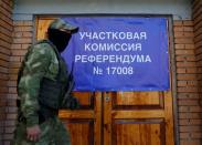 Un militar de la autoproclamada República Popular de Donetsk pasa junto a una pancarta a las puertas de un colegio electoral antes del referéndum previsto sobre la unión de la República Popular de Donetsk a Rusia, en Donetsk