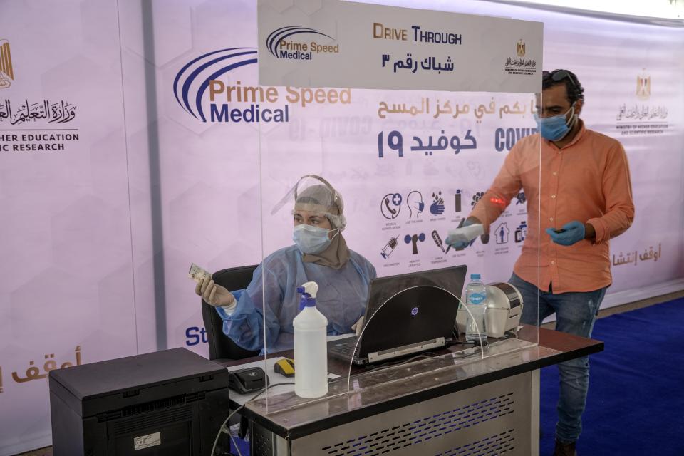 A health worker wearing protective gear prepares to take swab samples from people queuing in their cars to test for the coronavirus at a drive-through COVID-19 screening center at Ain Shams University in Cairo, Egypt, Wednesday, June 17, 2020. (AP Photo/Nariman El-Mofty)