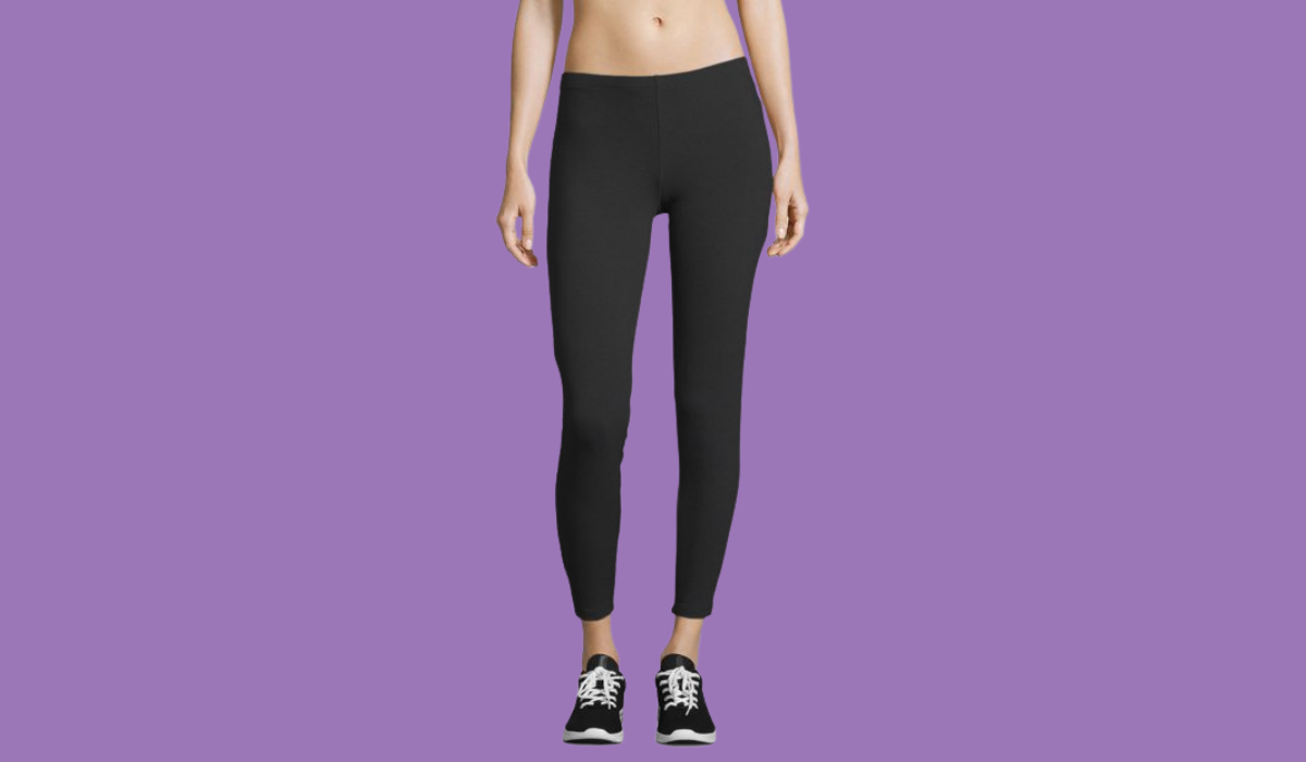 The torso and legs of a woman wearing black leggings with black sneakers
