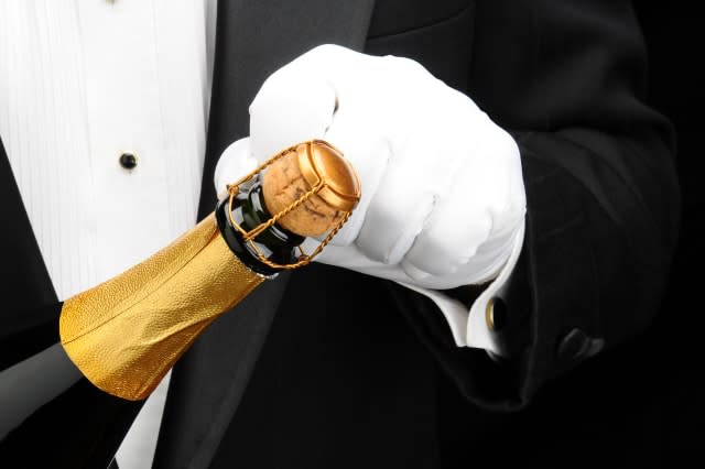 Closeup of a waiter opening a bottle of champagne.