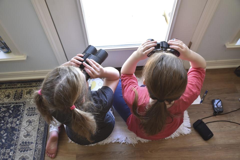 This image provided by Macaulay Library/Cornell Lab of Ornithology shows two girls watching birds through a window with binoculars, bird lists and cameras in Elm Grove, Louisiana, during the Great Backyard Bird Count in February 2022. About 385,000 people from 192 countries took part in the 2022 count, and their results have been used by scientists to study bird populations worldwide. (Emily Tubbs/Macaulay Library/Cornell Lab of Ornithology via AP)