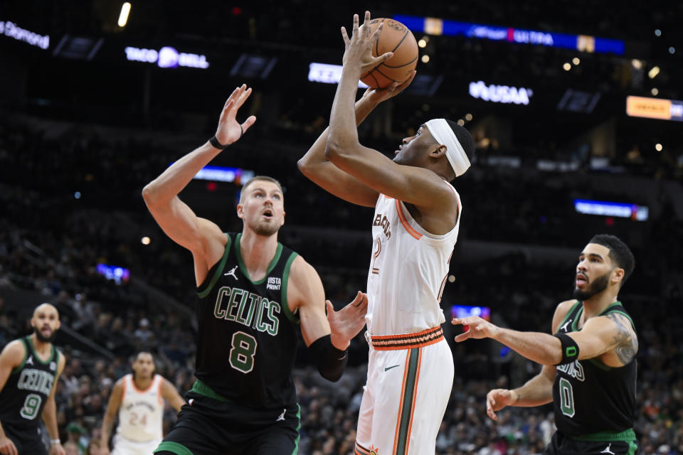 San Antonio Spurs' Malaki Branham attempts to shoot as he is defended by Boston Celtics' Kristaps Porzingis (8) and Jayson Tatum (0) during the first half of an NBA basketball game, Sunday, Dec. 31, 2023, in San Antonio. (AP Photo/Darren Abate)