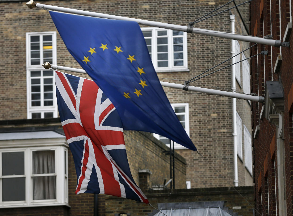 A EU flag hangs beside the Union Jack at the Europa House in London, Wednesday, Feb. 17, 2016. Britain's Prime Minister David Cameron will attend a EU summit starting tomorrow. (AP Photo/Frank Augstein)