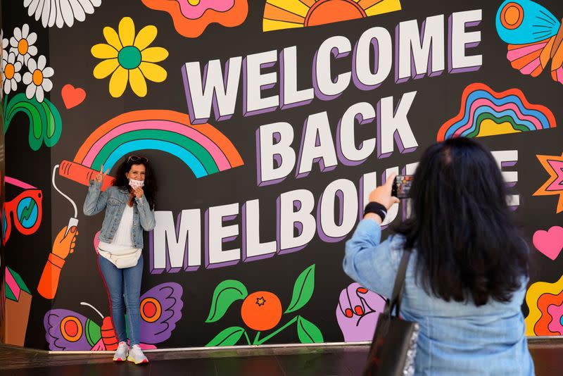 People take photos in front of a 'Welcome Back' sign after coronavirus disease restrictions were eased in Melbourne