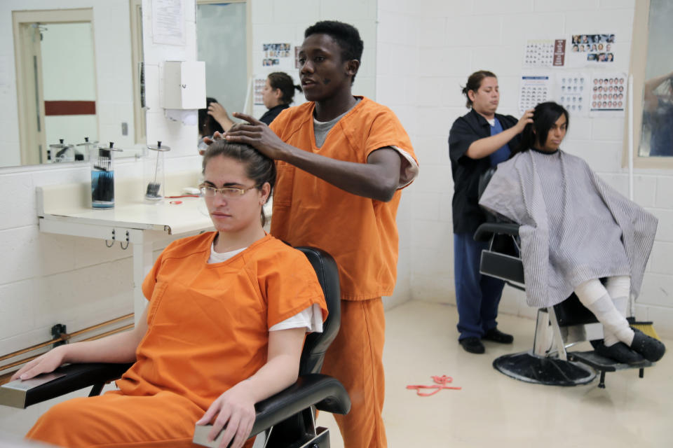 This June 6, 2019 image provided by U.S. Immigration and Customs Enforcement shows immigration detainees using a beauty salon that has been set up at a dedicated unit for transgender women in the Cibola County Correctional Center in Milan, N.M. (Ron Rogers/U.S. Immigration and Customs Enforcement via AP)