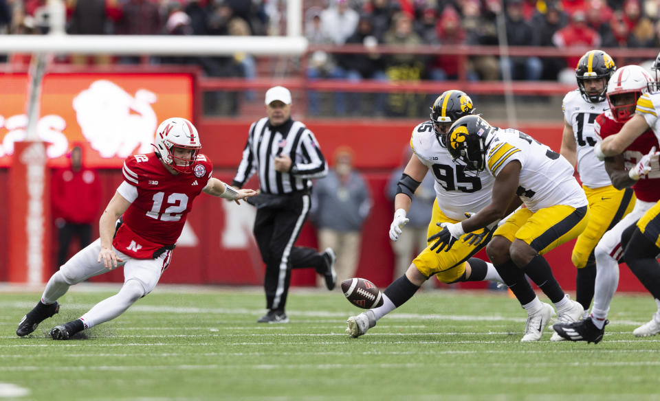 Nebraska quarterback Chubba Purdy, from left, fumbles the ball against Iowa's Aaron Graves and Jay Higgins during the second half of an NCAA college football game Friday, Nov. 24, 2023, in Lincoln, Neb. The fumble was recovered by Nebraska. (AP Photo/Rebecca S. Gratz)