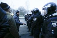 Protesters, who planned to stop buses with passengers from the Ukrainian aircraft chartered by the Ukrainian government for evacuation from the Chinese city of Wuhan, speak to Ukrainian riot police blocking the road outside Novi Sarzhany, Ukraine, Thursday, Feb. 20, 2020. Several hundred residents in Ukraine's Poltava region protested to stop officials from quarantining the evacuees in their village because they feared becoming infected. Demonstrators put up road blocks and burned tires, while Ukrainian media reported that there were clashes with police, and more than 10 people were detained. (AP Photo/Efrem Lukatsky)