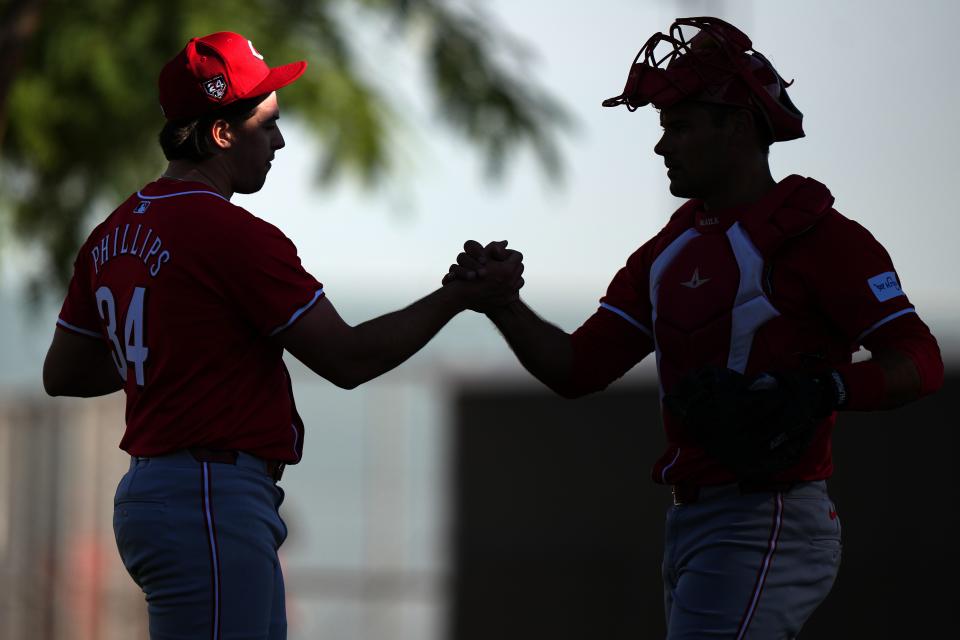 Cincinnati Reds starting pitcher Connor Phillips (34) and Cincinnati Reds catcher Luke Maile (22) embrace after a bullpen session during spring training workouts, Thursday, Feb. 15, 2024, at the team’s spring training facility in Goodyear, Ariz.