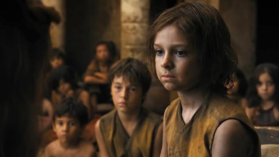 A poor child with many more behind them sits and looks sad in Flea Bottom on Game of Thrones