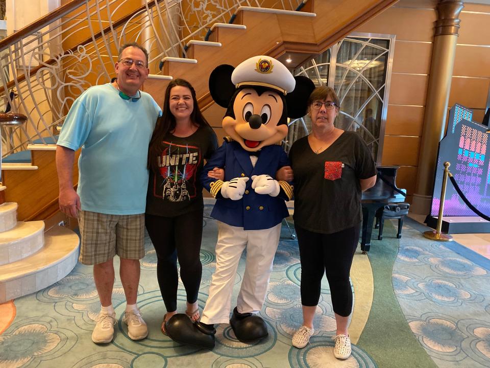 megan and her family posing with mickey mouse on a disney magic cruise ship