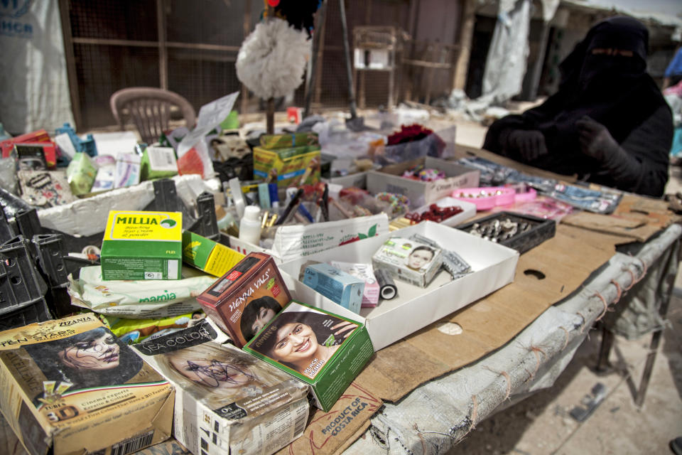 A woman wearing a niqab, the veil worn by the most conservative Muslim women, sells products for women in the marketplace at al-Hol camp that houses some 60,000 refugees, including families and supporters of the Islamic State group, many of them foreign nationals, in Hasakeh province, Syria, Saturday, May 1, 2021. Kurdish officials say security has improved at the sprawling camp in northeast Syria, but concerns are growing of a coronavirus outbreak in the facility. (AP Photo/Baderkhan Ahmad)