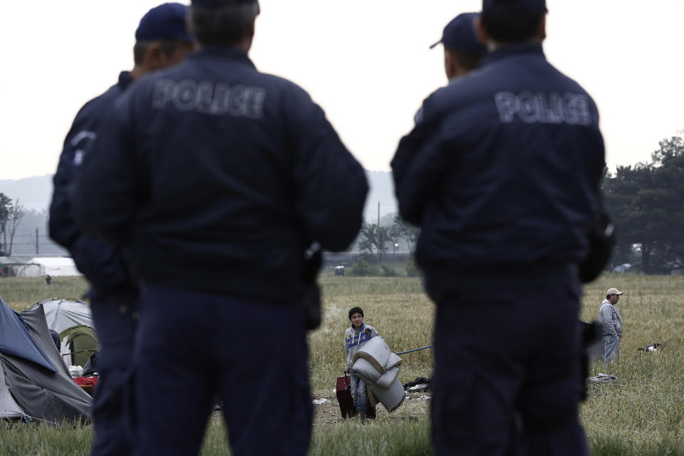 <p>A refugee boy carries his belongings behind police officers at a camp near Idomeni, Greece, on May 24, 2016, as evacuations begin. (Yannis Kolesidis/AP) </p>