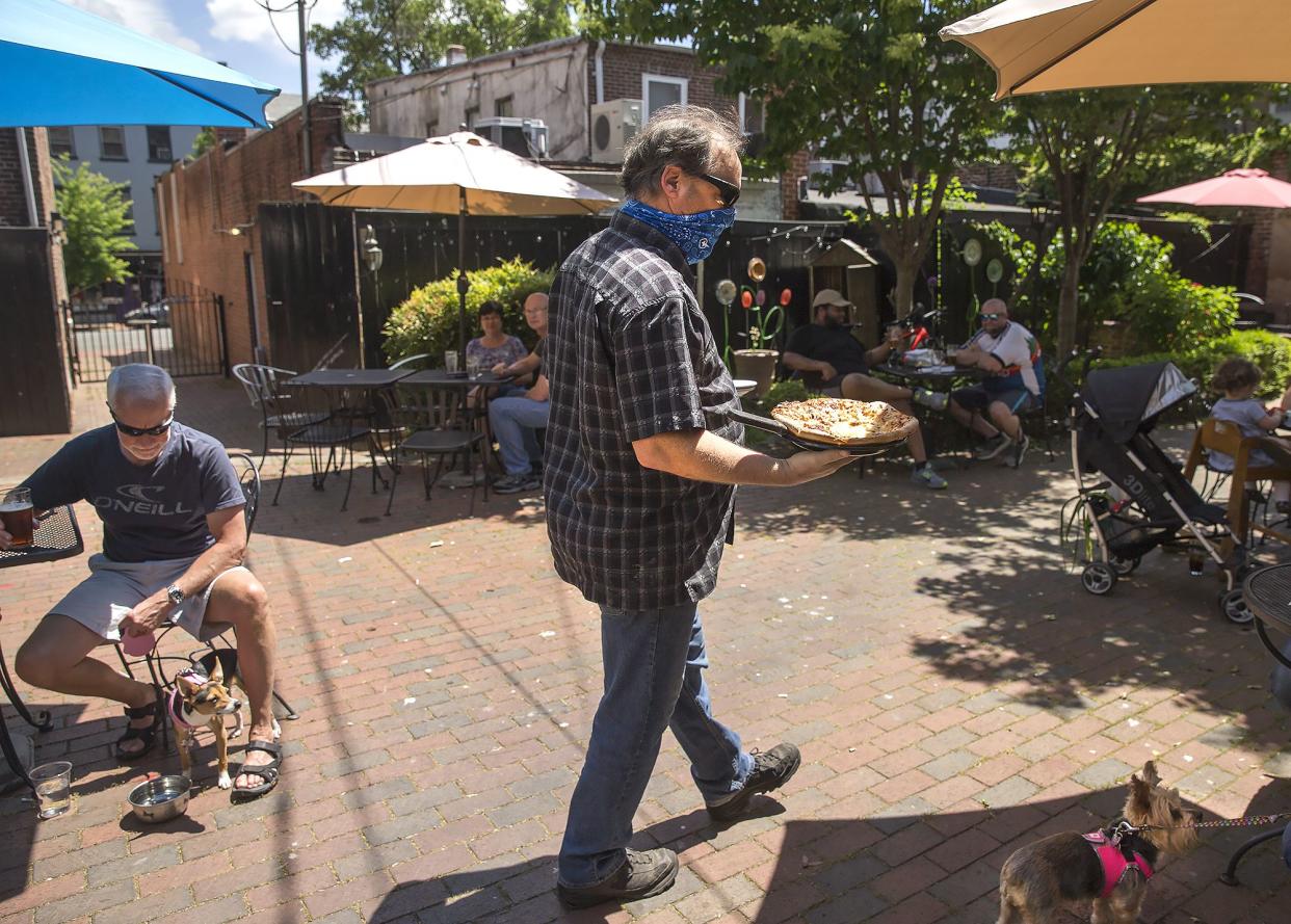 Michael Mansfield, center, of J.Brian's Tap Room, serves food at the downtown Fredericksburg, Va. eatery on Saturday, May 16, 2020, during the coronavirus pandemic. Several Fredericksburg restaurants opened their outdoor areas for the first phase of re-opening during the pandemic.