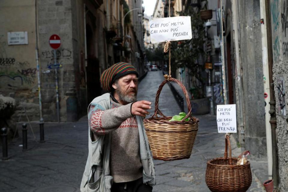 A man reaches for a basket where people can donate or take food in Naples