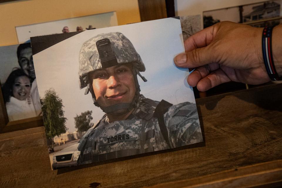 Le Roy Torres holds a photograph of himself from 2008 during his tour as an Army Reserve captain in Iraq, where he was exposed to toxic burn pits.