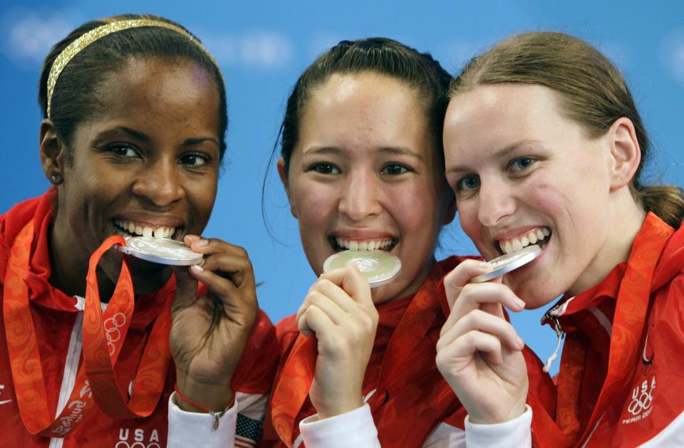 Erinn Smart, left, Emily Cross, center, and Hanna Thompson, right, of the USA bite their silver medals from the women's team foil at fencing during the Beijing 2008 Olympics in Beijing Saturday, Aug. 16, 2008.