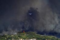 A Russian aircraft operates during a wildfire near ancient Olympia, Wednesday, Aug. 4, 2021. Greece evacuated people in boats from an island beach Wednesday amid heavy smoke from a nearby wildfire and fire crews fought elsewhere to keep flames away from the birthplace of the ancient Olympic Games as the country sweltered under a record heat wave. (Giannis Spyrounis/ilialive.gr via AP)