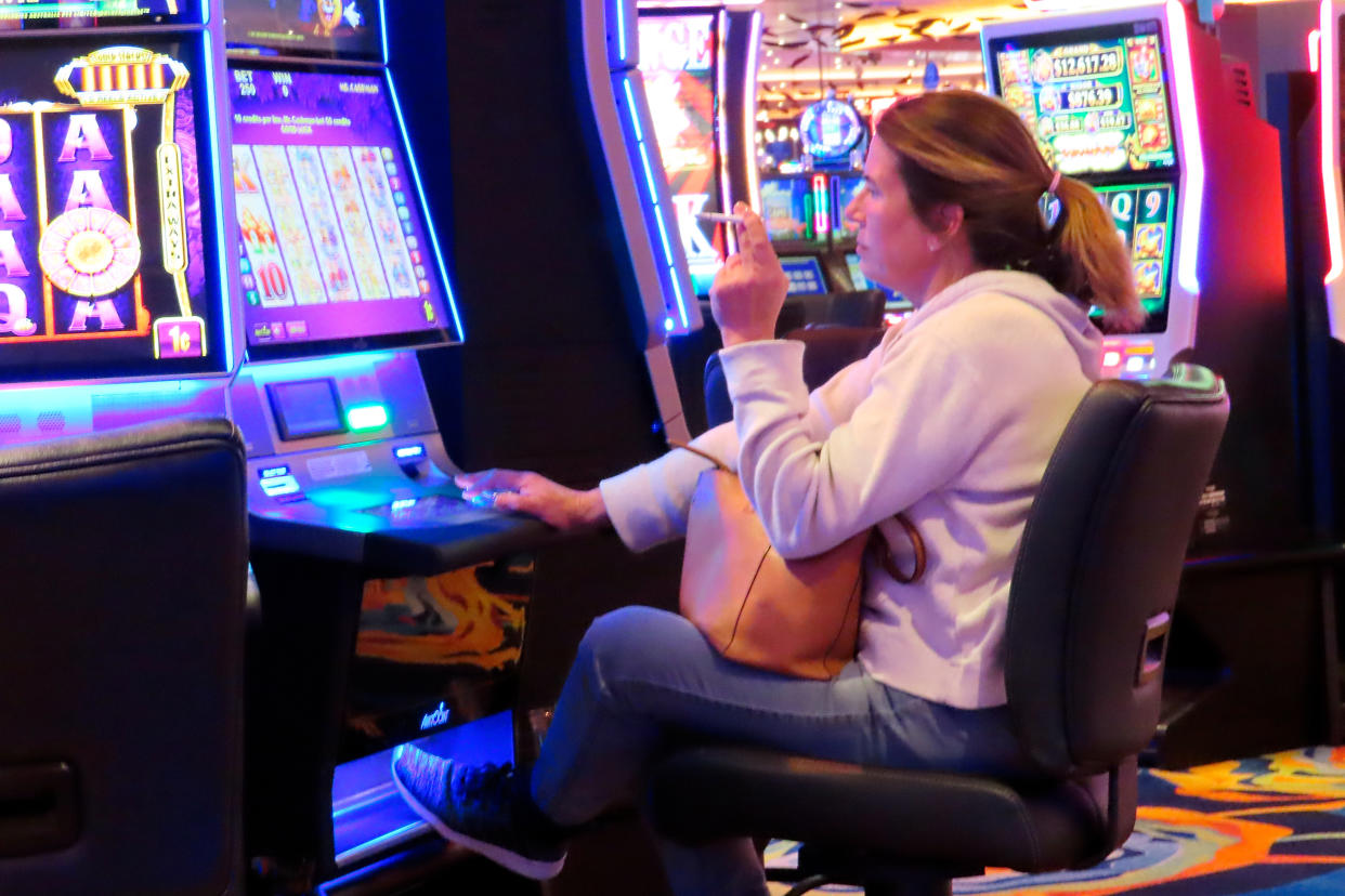 FILE - A woman smokes while playing a slot machine at the Ocean Casino Resort on Feb. 10, 2022, in Atlantic City, N.J. A report issued Friday, June 17, 2022, by a Las Vegas gambling research company suggested that ending smoking in casinos will not result in significant financial harm to the businesses. (AP Photo/Wayne Parry, File)