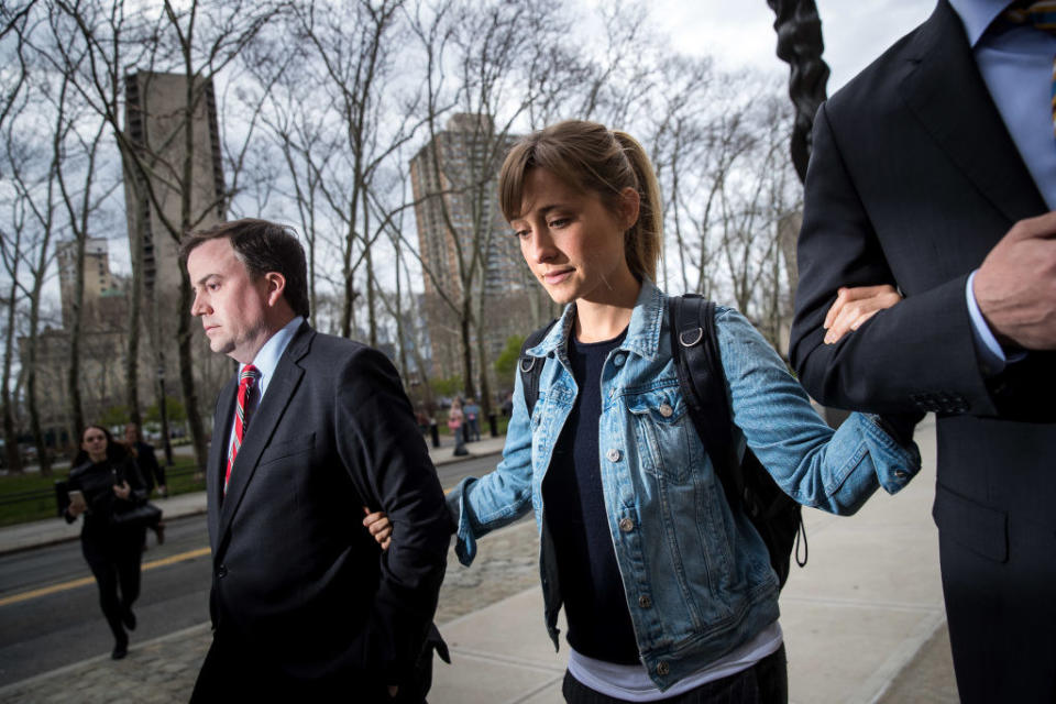 woman walking with her arms linked to two men walking on each side of her