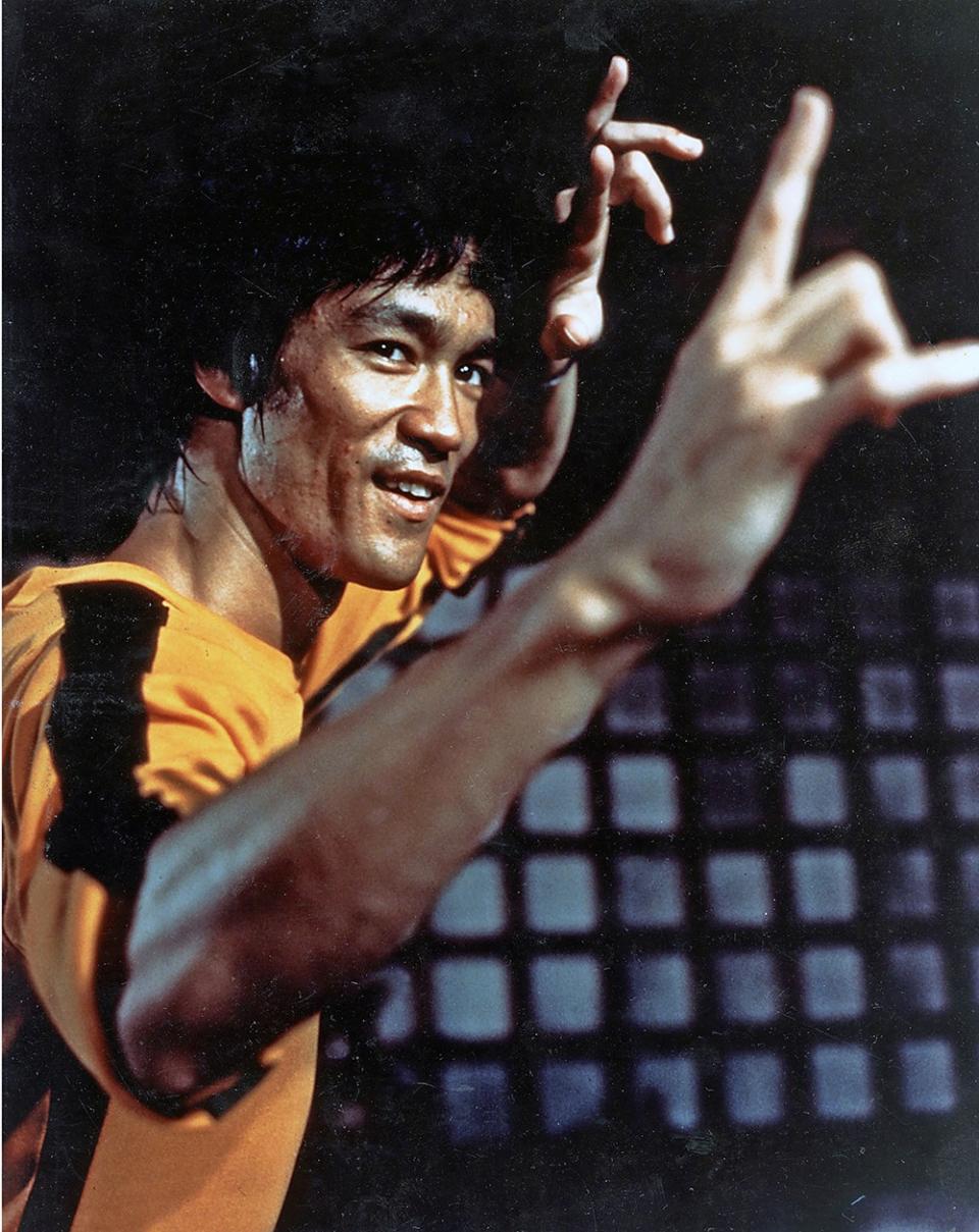 Bruce Lee in a martial arts stand smirking