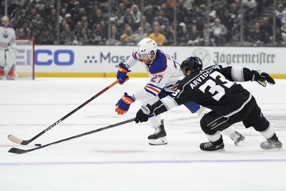 Edmonton Oilers defenseman Brett Kulak, left, reaches for the puck along with Los Angeles Kings right wing Viktor Arvidsson during Game 3 of an NHL hockey Stanley Cup first-round playoff series Friday, April 26, 2024, in Los Angeles. (AP Photo/Mark J. Terrill)