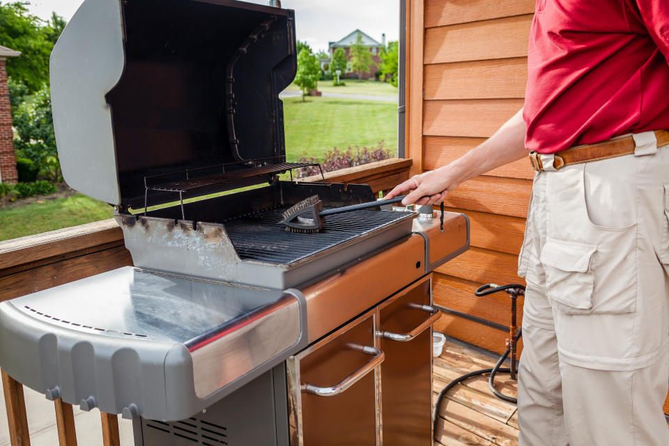 A man is cleaning grill grates with a brush