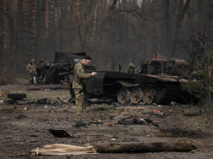 A Ukrainian serviceman takes a photo of a dead Russian soldier after Ukrainian forces overran a Russian position outside Kyiv, Ukraine, Thursday, March 31, 2022.