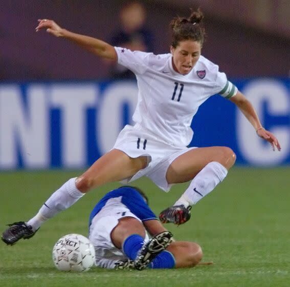 Julie Foudy leaps over Brazil's Maria De Souza Diaz to control the ball during a Gold Cup match