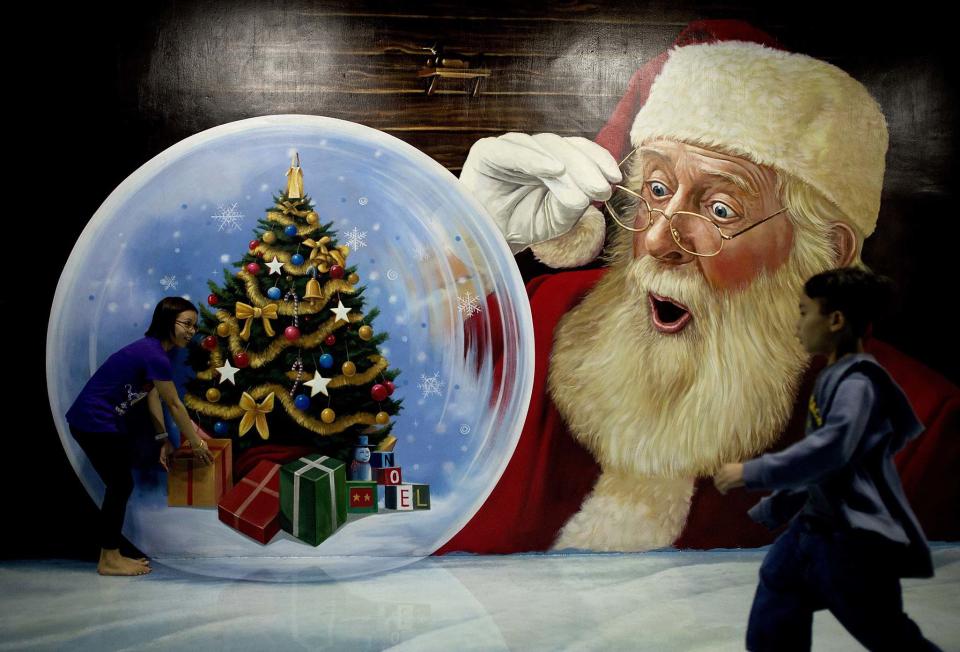 People gather around a three-dimensional painting of Santa Claus entitled "Santa's Christmas Gift" on Dec. 24, 2014 at the Art in Island interactive museum in Manila, Philippines.