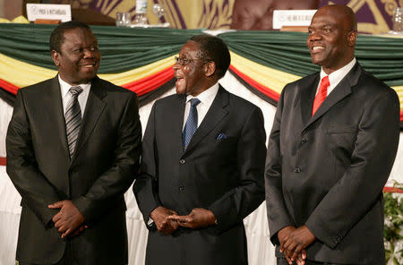 FILE PHOTO - Zimbabwe's President Robert Mugabe laughs with opposition leader Morgan Tsvangirai (L) and Arthur Mutambara, leader of breakaway faction of the main Zimbabwean opposition group Movement For Democratic Change (MDC), after signing a power-sharing deal at Rainbow Towers hotel in Harare, Zimbabwe September 15, 2008. REUTERS/Philimon Bulawayo/File Photo