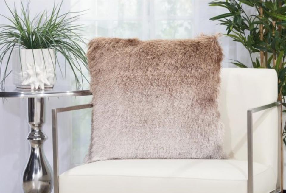 A beige ombre shag pillow on a white chair