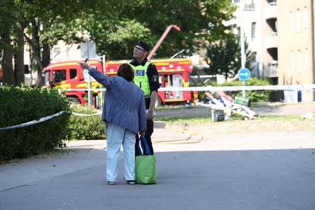 A police officer talks to a displaced resident after a block of flats was hit by an explosion in Linkoping