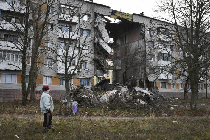 A woman passes by an apartment building damaged following by Russian shelling in Bakhmut, the site of the heaviest battles with the Russian troops, in the Donetsk region, Ukraine, Sunday, Dec. 11, 2022. (AP Photo/Andriy Andriyenko)