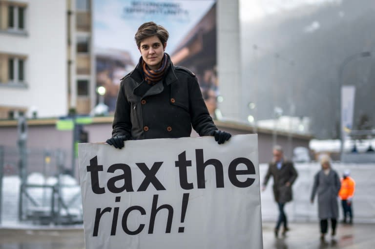 L'Autrichienne Marlene Engelhorn, qui a hérité de sa famille propriétaire du géant allemand de la chimie BASF, tient une pancarte "Taxez les riches !" à l'ouverture du Forum économique mondial (WEF) de Davos, le 15 janvier 2024 en Suisse (Fabrice COFFRINI)