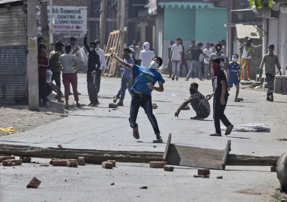 A Kashmiri protester throws stones on government forces as they attempt to march on the streets in solidarity with rebels engaged in a gunbattle with soldiers, in Srinagar, Indian controlled Kashmir, Thursday, Sept. 17, 2020. The gunfight erupted shortly after scores of counterinsurgency police and soldiers launched an operation based on a tip about the presence of militants in a Srinagar neighborhood, Pankaj Singh, an Indian paramilitary spokesman, said. (AP Photo/Mukhtar Khan)